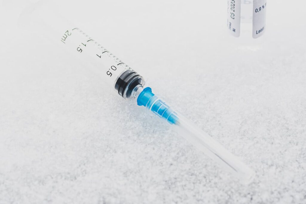 A medical syringe and a vial resting on a bed of ice.